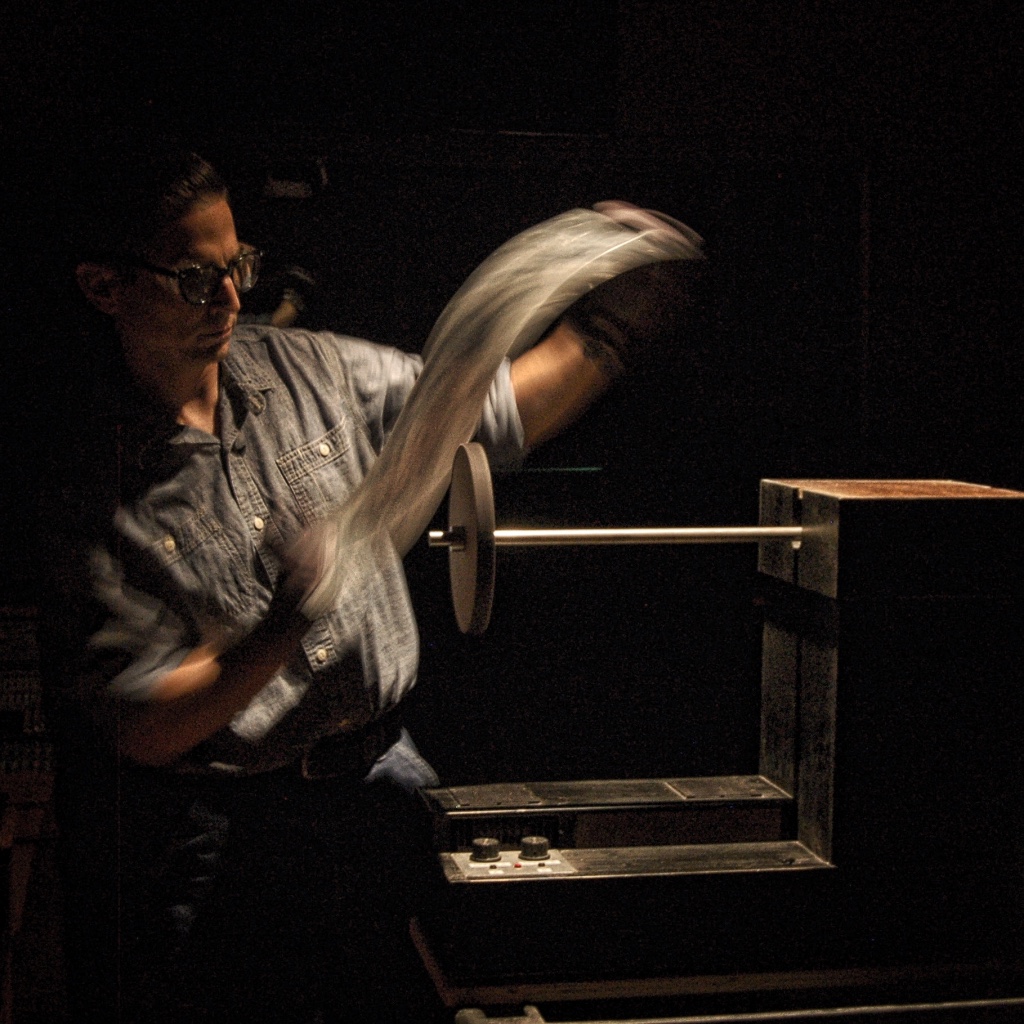 A sound artist manipulates a piece of metal on a spinning friction wheel.